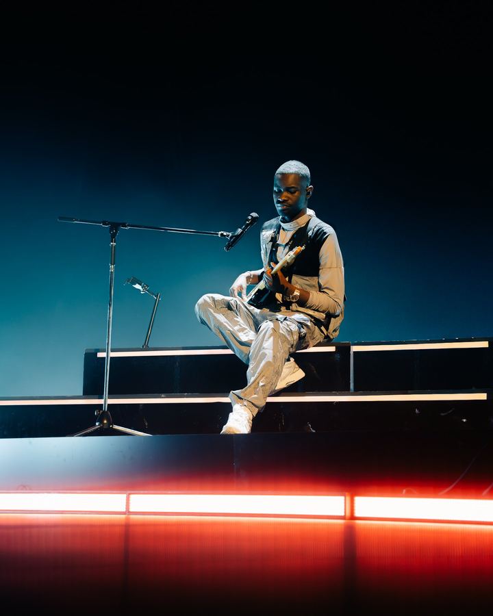 Artist seated on stage, red wash